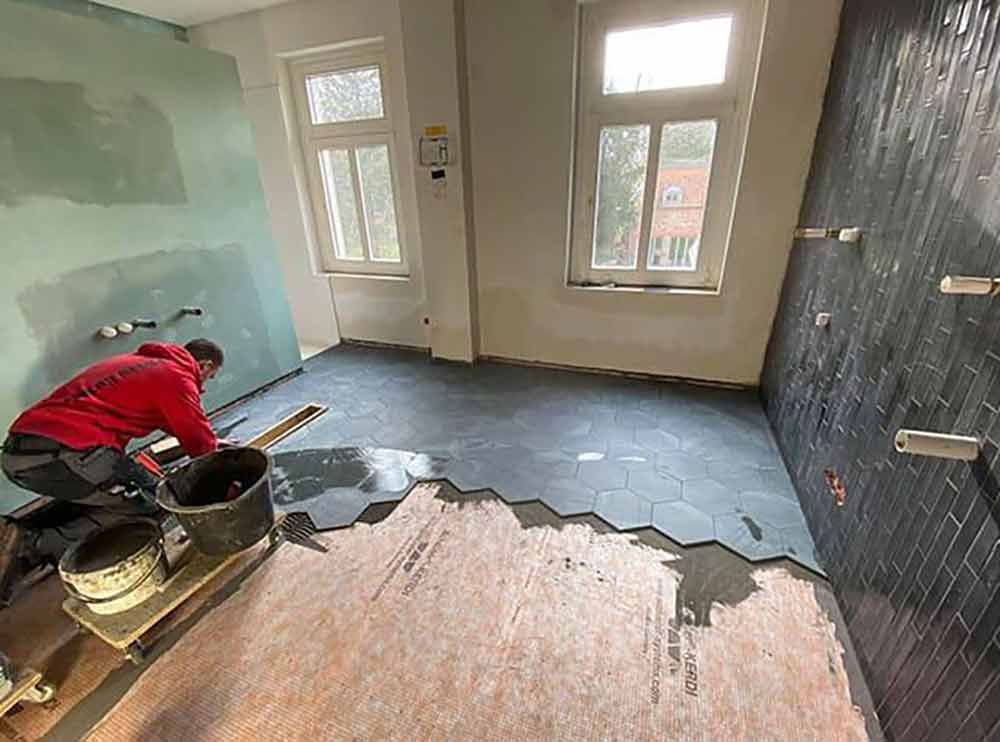 Ein Mann arbeitet auf einem gefliesten Boden in einem Raum.