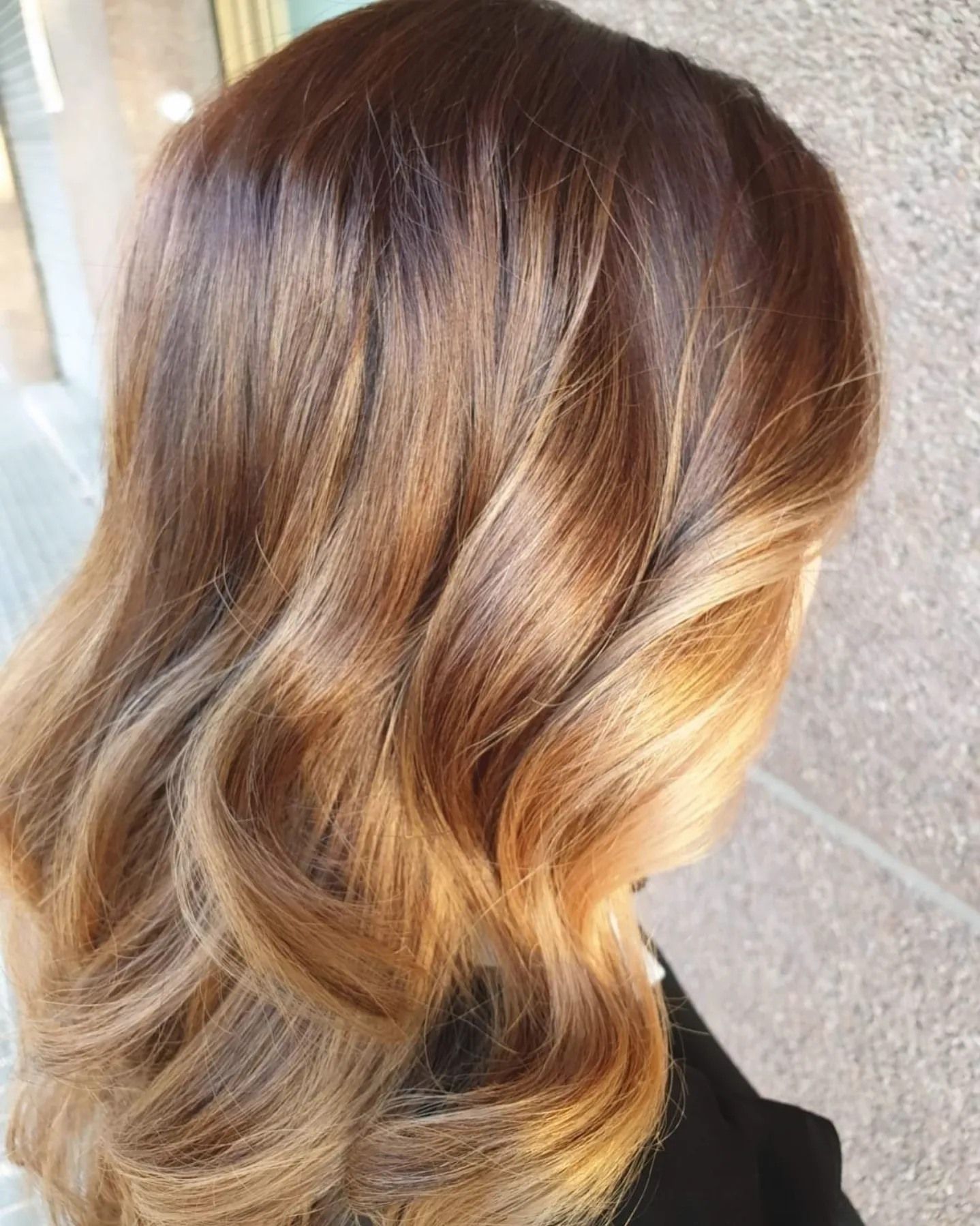 Una mujer con cabello largo y castaño está parada frente a un edificio.