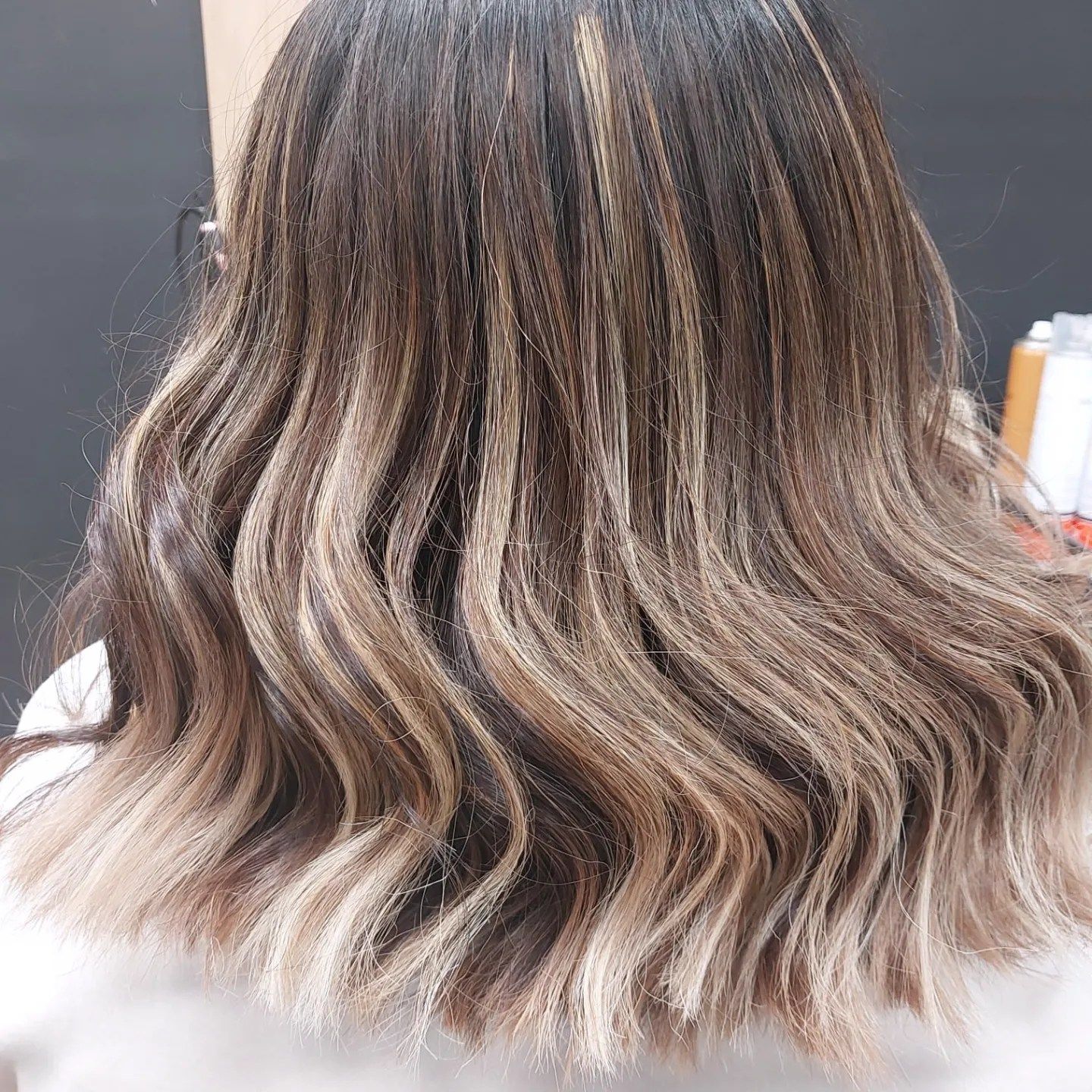 Una mujer con cabello largo y ondulado está sentada en una silla.