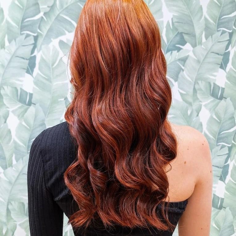 Una mujer con cabello largo y rojo lleva una blusa negra.