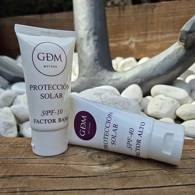 Dos tubos de protector solar gdm están sobre una mesa de madera.