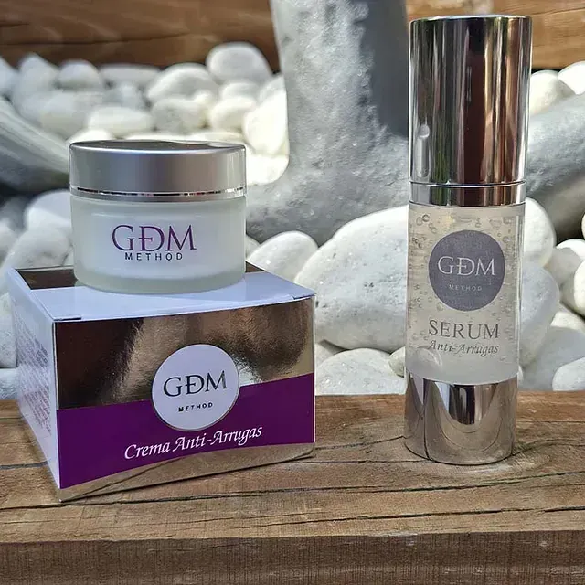 Dos botellas de cosméticos GDM están sobre una mesa de madera.