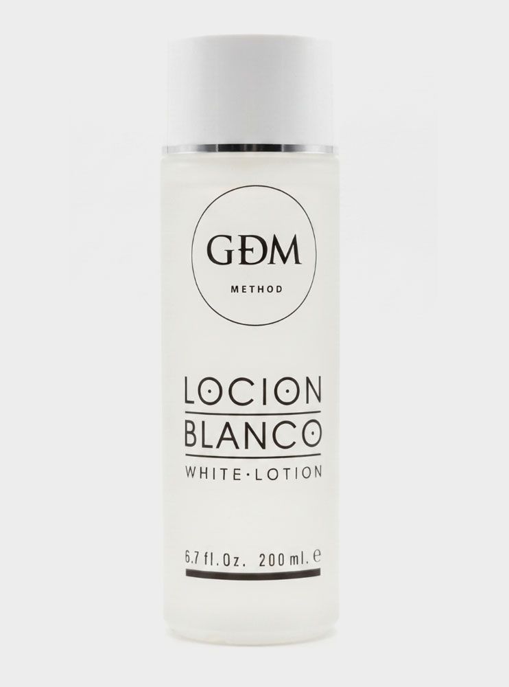 Botella blanca de GDM Metódico Loción Blanco con texto negro sobre fondo liso.