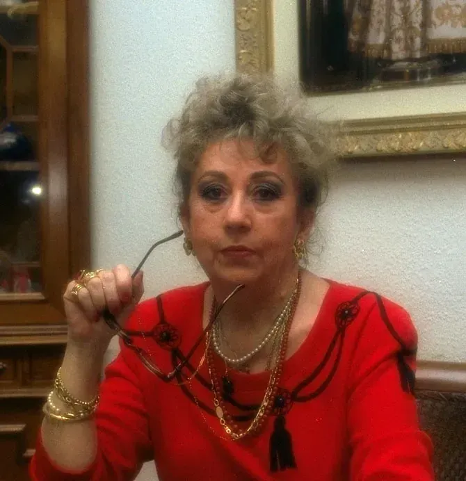 Una mujer con una camisa roja sostiene un par de gafas.
