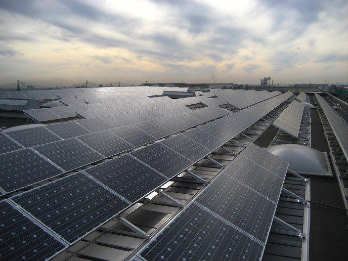 Paneles solares que cubren un tejado bajo un cielo nublado al atardecer.