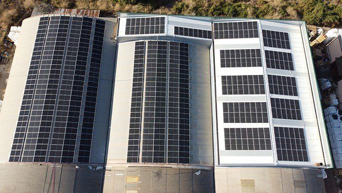 Vista aérea de una azotea cubierta con hileras de paneles solares y tragaluces.