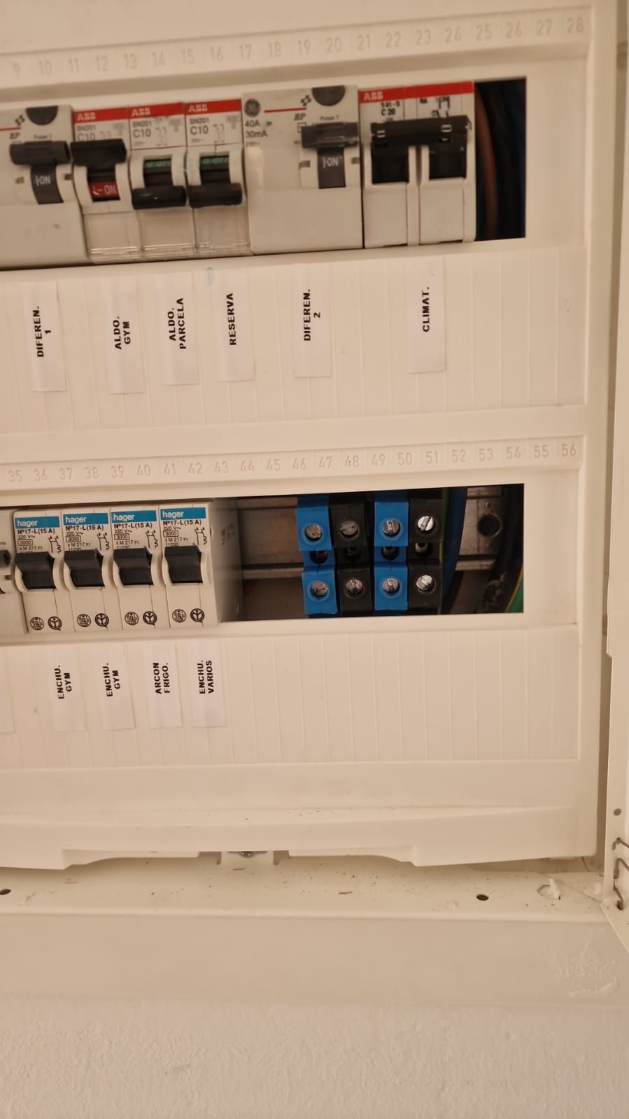 Panel eléctrico blanco con disyuntores y terminales de cableado azul y negro.