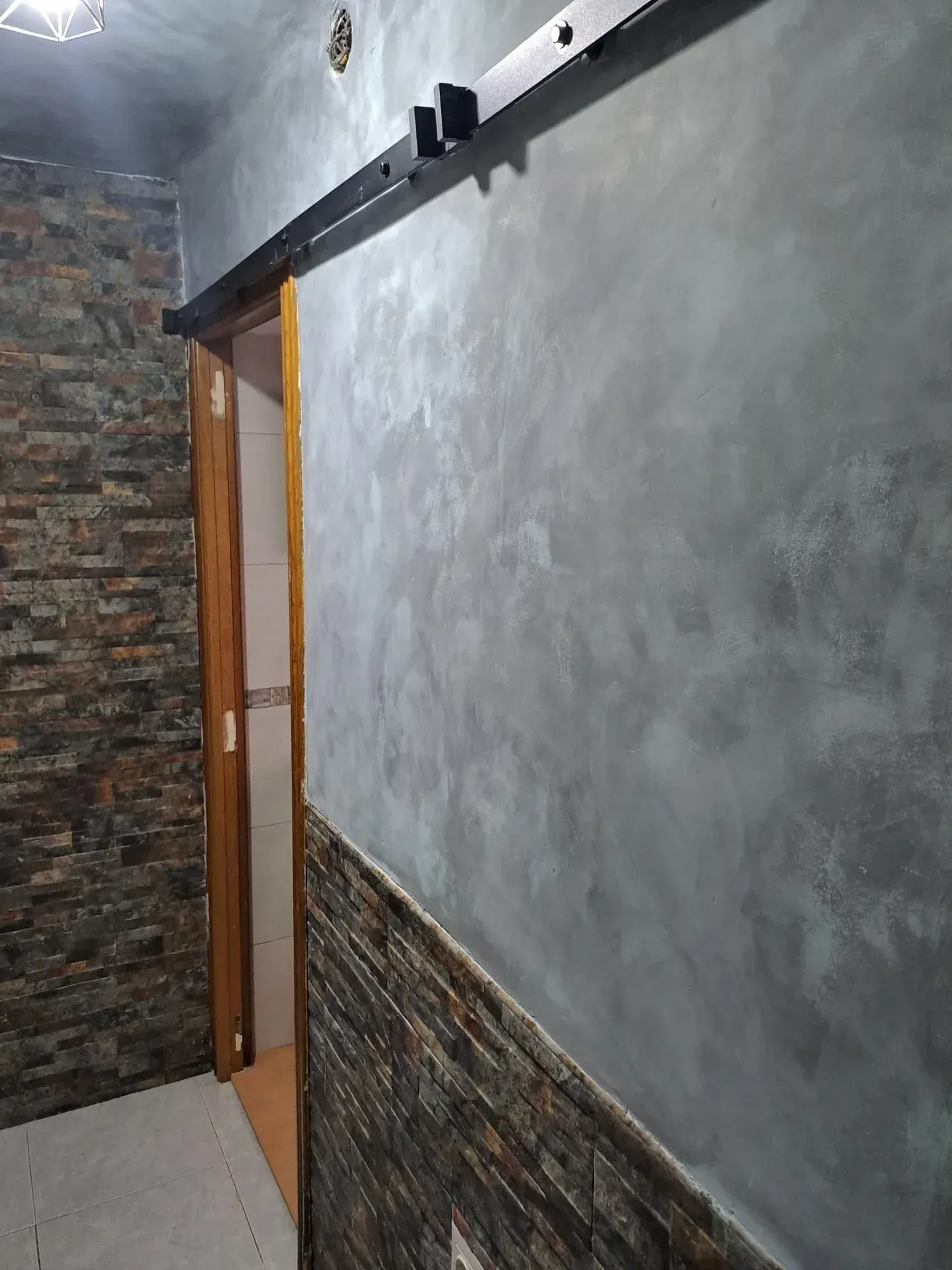 Un pasillo con una puerta corrediza y una pared de ladrillo.
