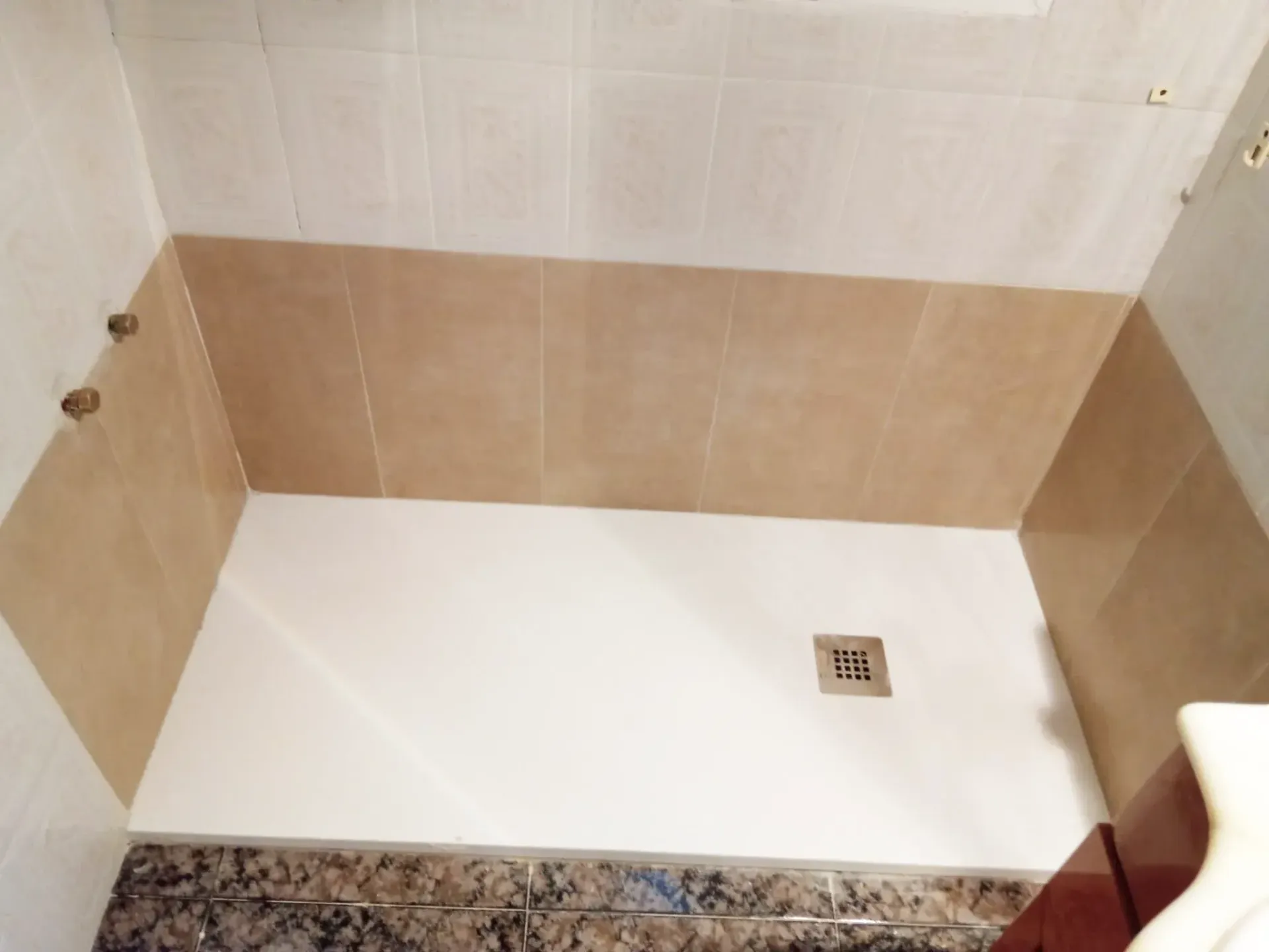 Un baño con ducha a ras de suelo y lavabo.