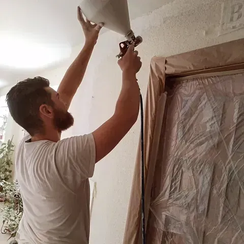 Hombre pintando techo con pintura y aparato de aerosol