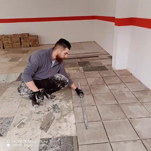 Un hombre está arrodillado sobre un suelo de baldosas.