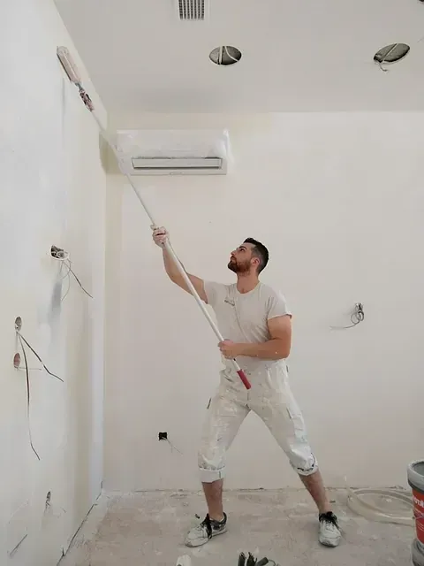 Un hombre está pintando una pared con un rodillo.