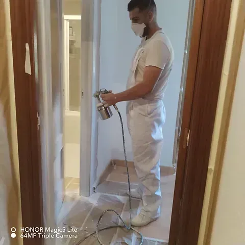 Un hombre que lleva una máscara está rociando pintura en una pared.