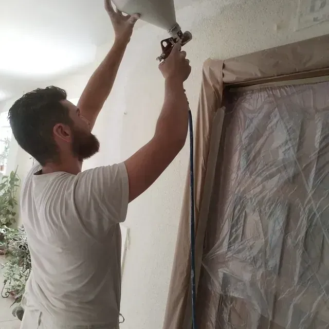 Un hombre con una camisa blanca está rociando pintura en una pared