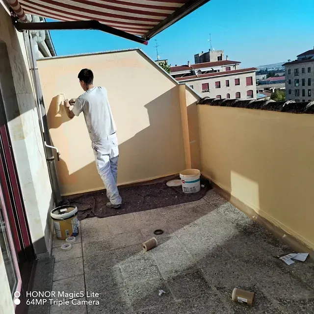 Un hombre está pintando una pared en un balcón.
