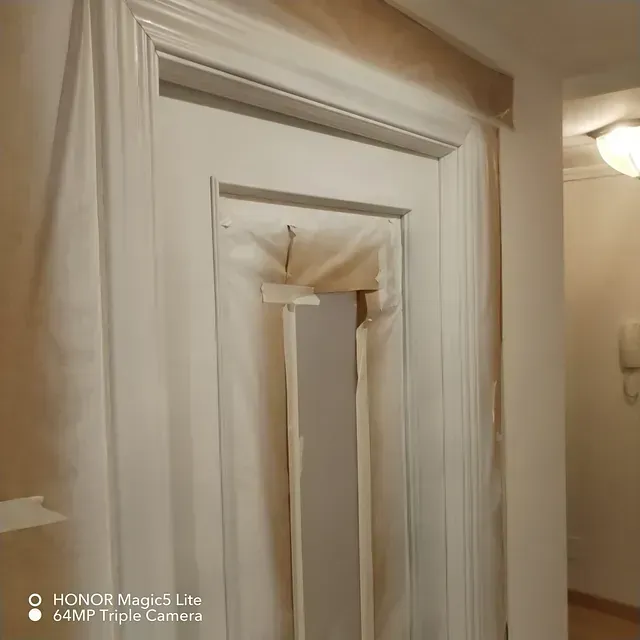 Una puerta blanca está cubierta con una tela blanca en un pasillo.