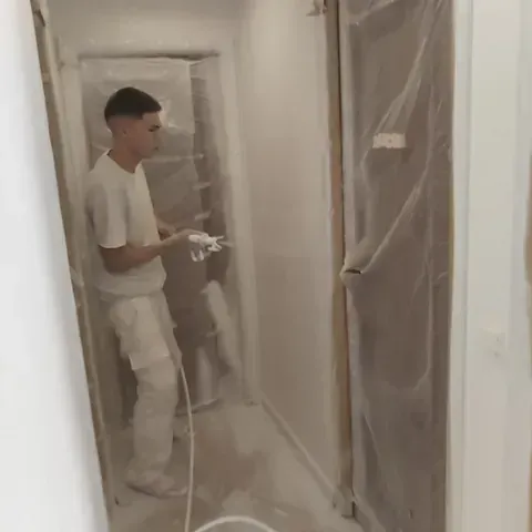 Un hombre está de pie en un pasillo cubierto de plástico.