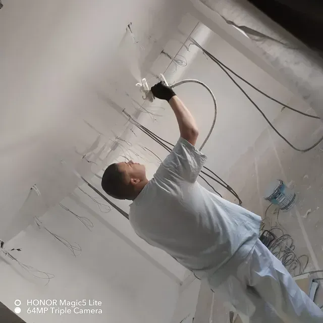 Un hombre está rociando una pared con una manguera.