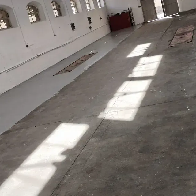 Una habitación grande con suelo de hormigón y paredes blancas.