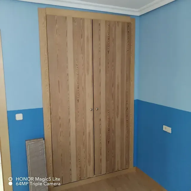 Una habitación con paredes azules y un armario de madera.