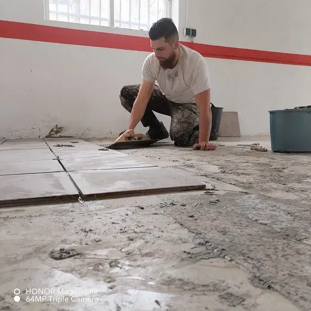 Un hombre está arrodillado en el suelo usando una paleta.