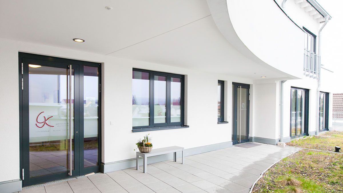 Ein weißes Gebäude mit vielen Fenstern und Türen.