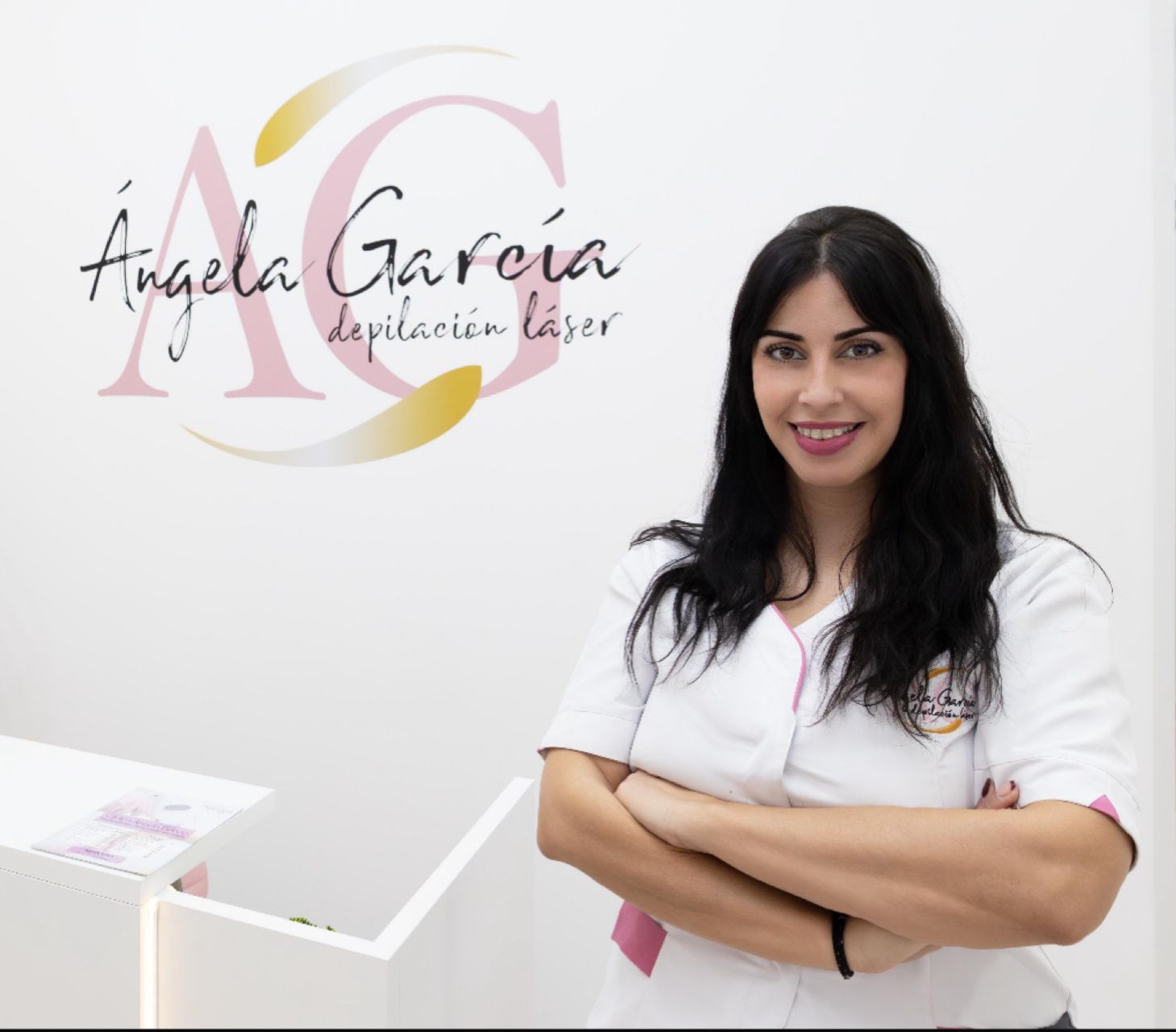 Woman with arms crossed smiling in front of a logo that says 
