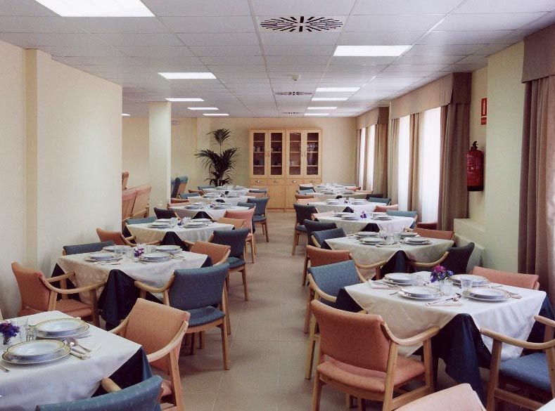 Un comedor con mesas y sillas y platos sobre ellas.