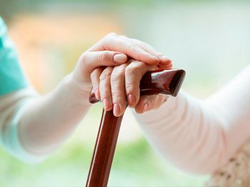 Una mujer sostiene la mano de otra mujer mientras sostiene un bastón.
