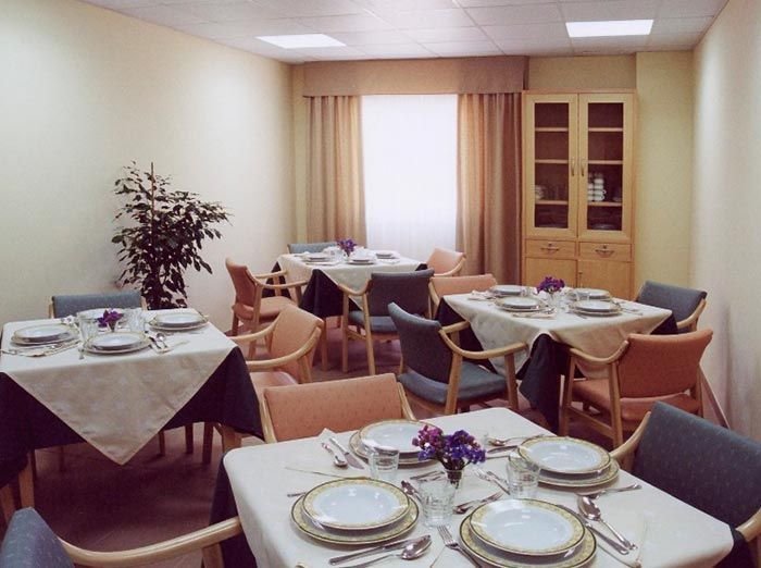 Un comedor con mesas y sillas preparadas para comer.