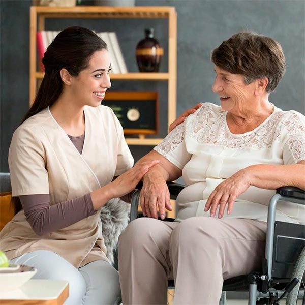 Una enfermera está hablando con una mujer mayor en silla de ruedas.