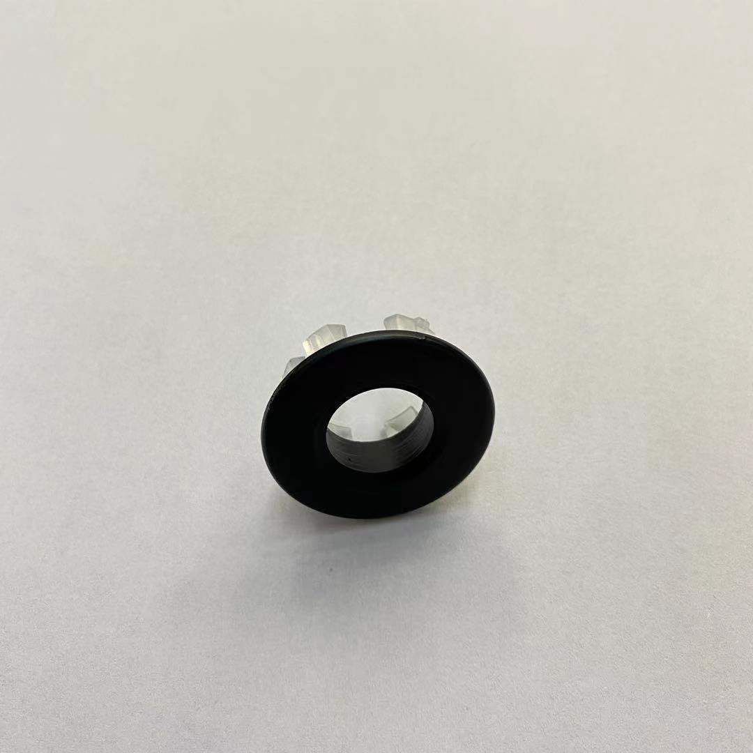 Un pequeño anillo de goma negro con un agujero en el medio está sobre una superficie blanca.