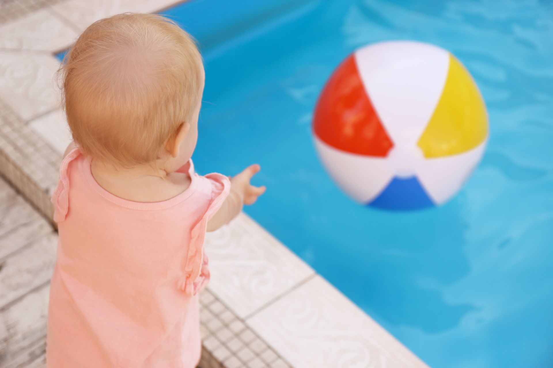 Enfant voulant attraper un ballon dans une piscine