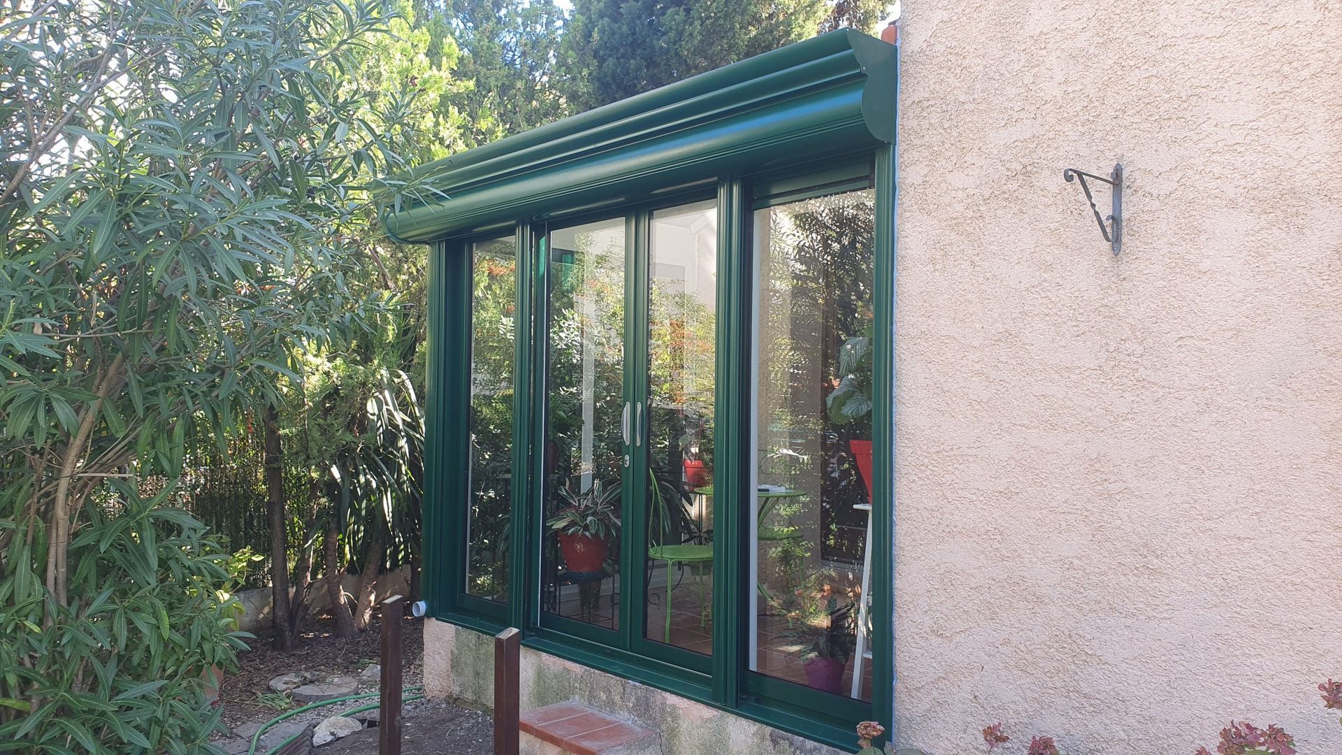 Fenêtres encadrées de vert avec un auvent vert sur un mur en stuc.