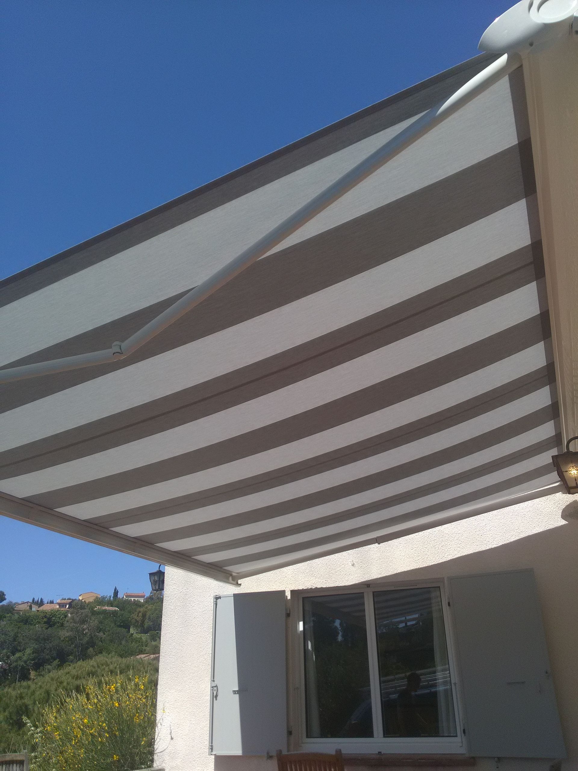 Auvent rayé s'étendant sur une fenêtre par une journée ensoleillée.