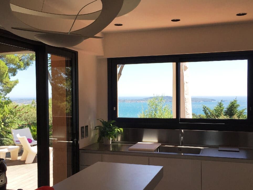 Cuisine avec de grandes fenêtres donnant sur l'océan. Une porte-fenêtre coulissante donne sur un patio.