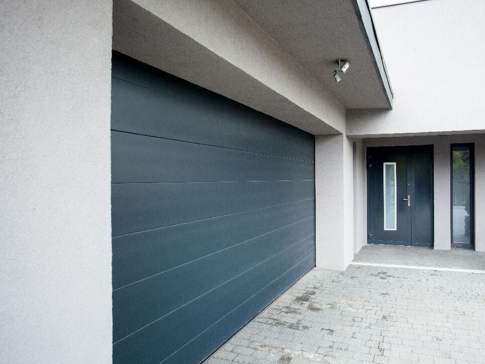 Porte de garage grise et porte d'entrée d'une maison moderne.