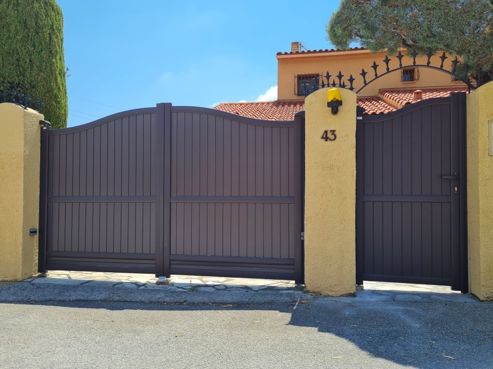 Entrée fermée marron d'une maison avec le numéro 43 sur un pilier jaune.
