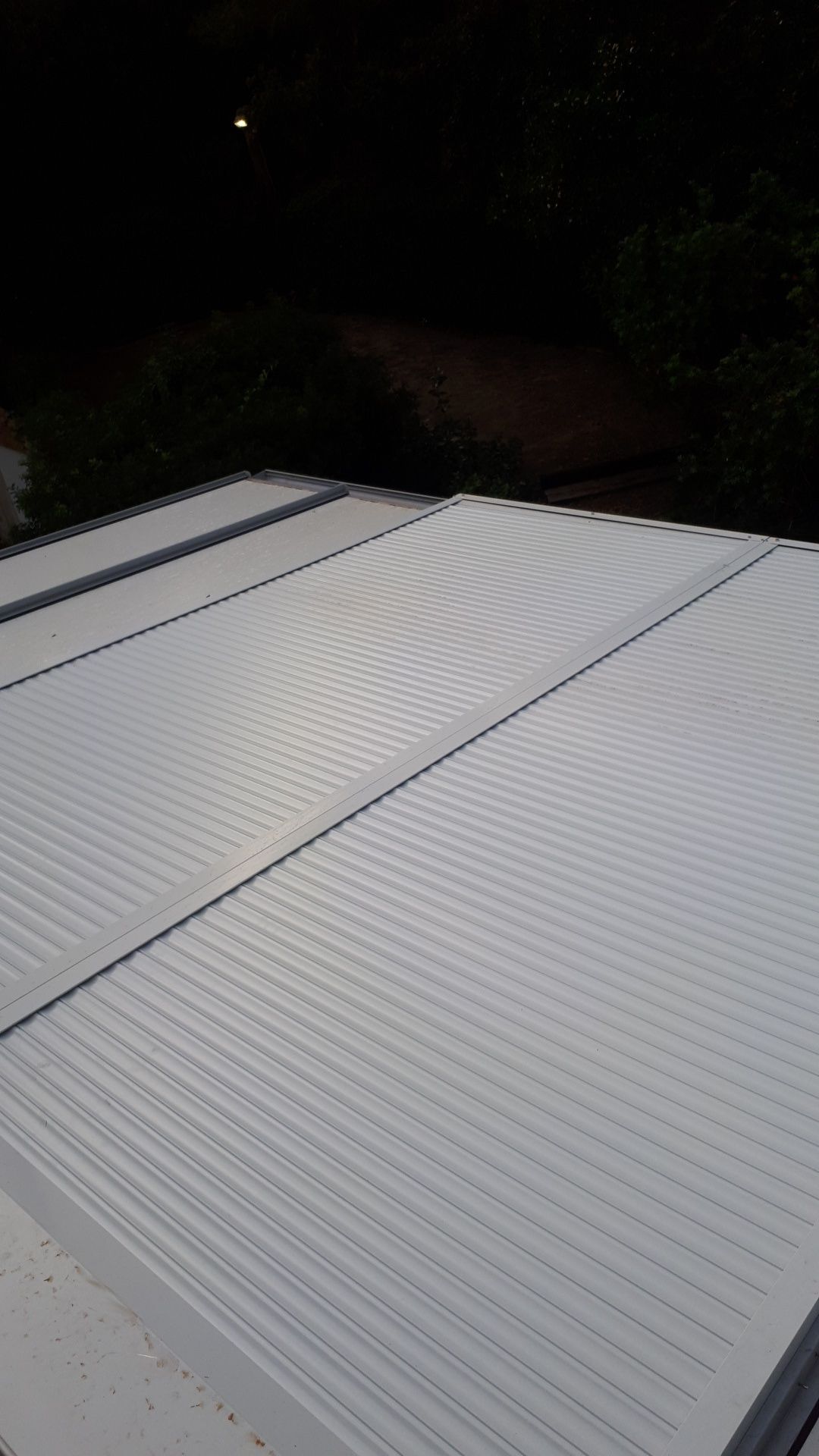 Toiture métallique à panneaux striés, vue d'en haut au crépuscule.