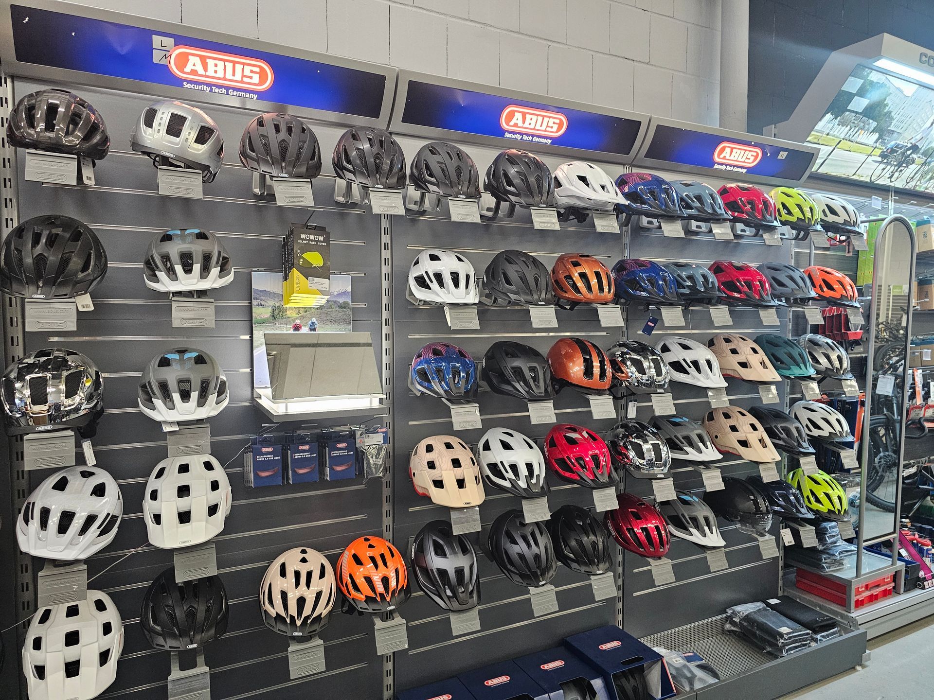 Große Auswahl an Fahrradhelmen im Fachgeschäft, übersichtlich an der Wand präsentiert