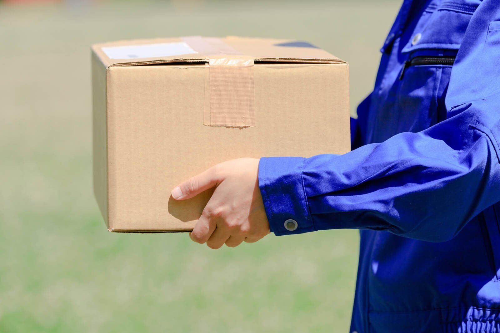 Gros plan sur un transporteur avec un vêtement bleu tenant une boîte