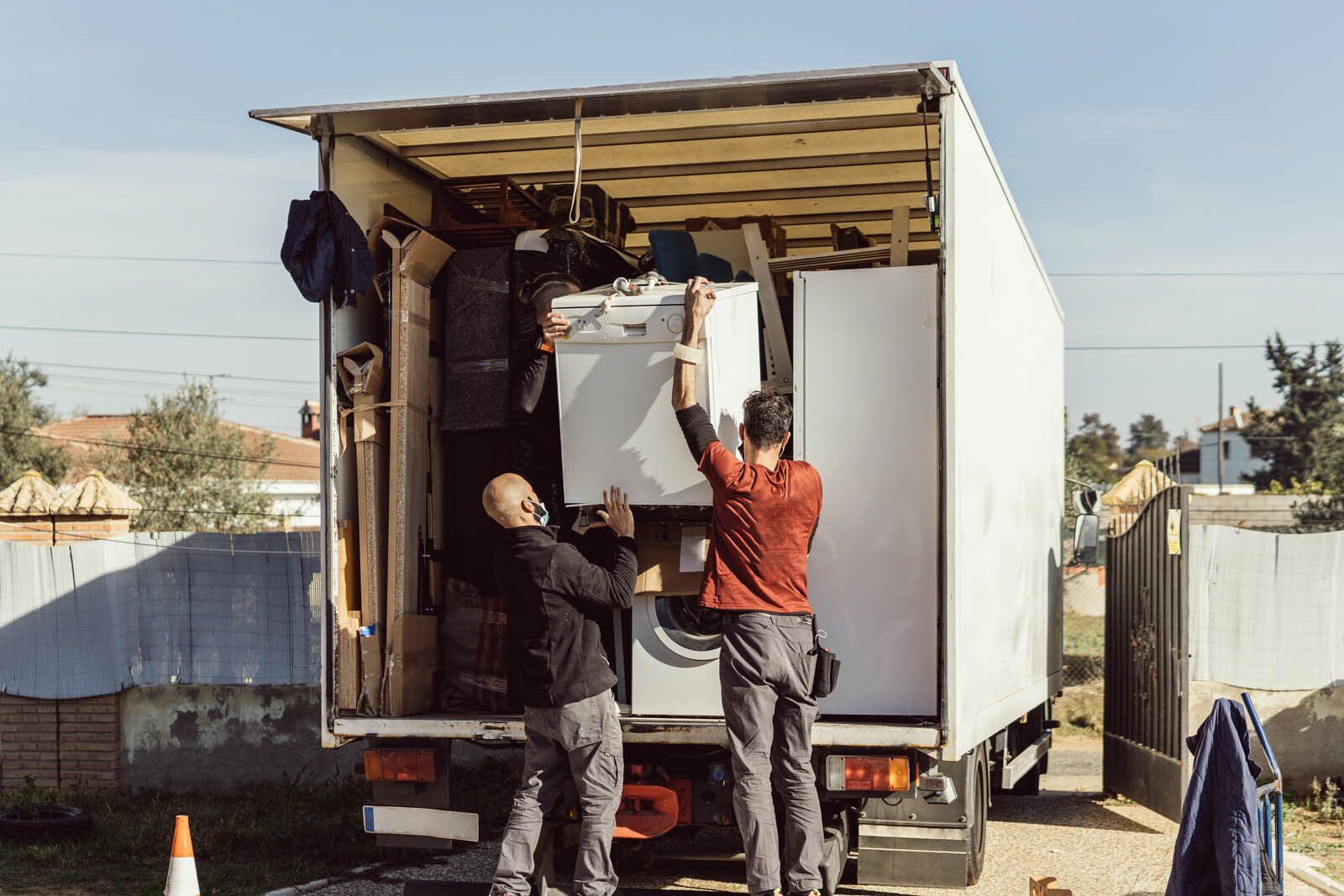 Trois transporteurs déchargent les meubles d'un camion blanc