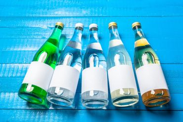 Cuatro botellas de agua están alineadas sobre una mesa de madera azul.