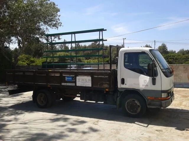 Um caminhão branco com uma caçamba de madeira está estacionado em um estacionamento.