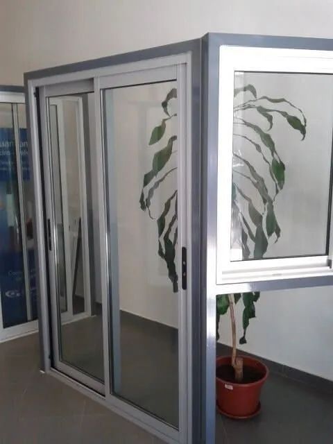 Uma planta em vaso está ao lado de uma janela em uma sala.