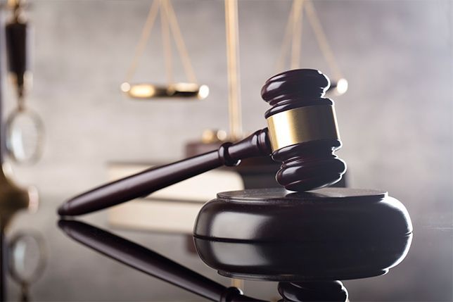 El mazo de un juez está sobre una mesa delante de una balanza de justicia.