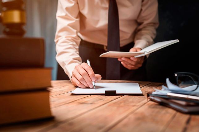 Un hombre está escribiendo en un trozo de papel mientras sostiene una tableta.