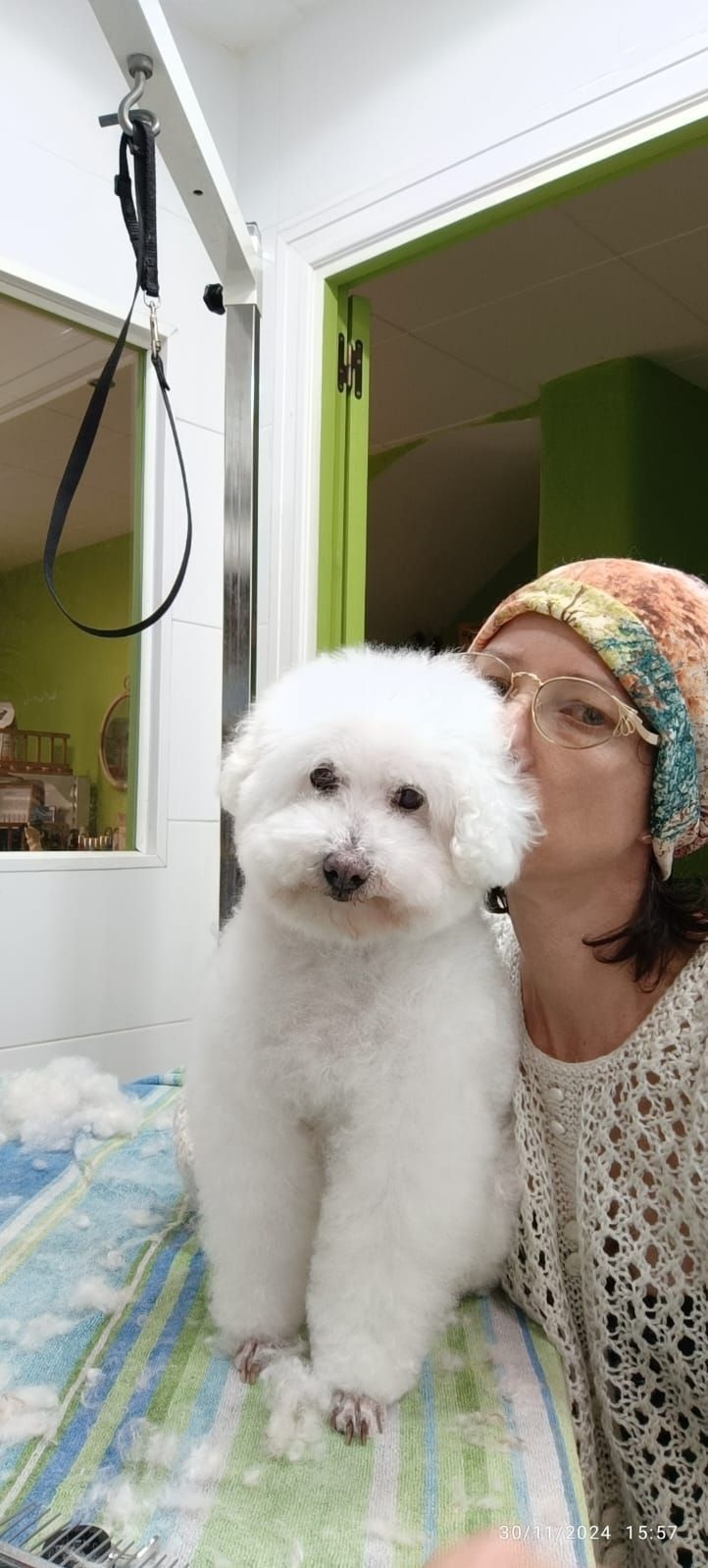 Una mujer besa a un pequeño perro blanco en la mejilla.