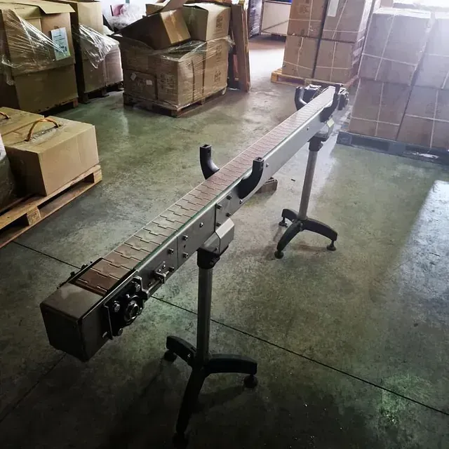 Una cinta transportadora se encuentra en un almacén rodeada de cajas.