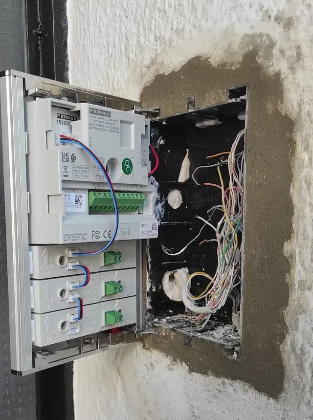 Una caja con cables saliendo de ella está apoyada en una pared.